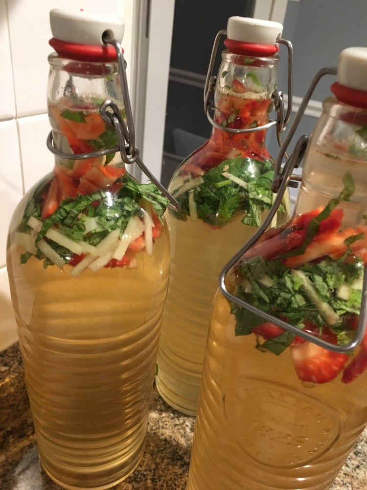 Making kombucha at home, three bottles of finished strawberry, basil and cucumber