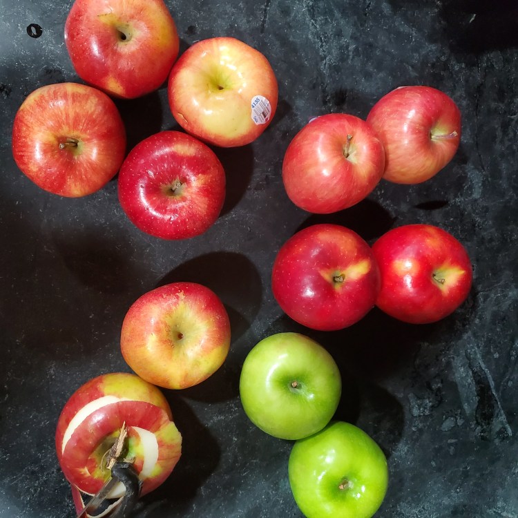 twelve apples, four different kinds on a black soapstone counter