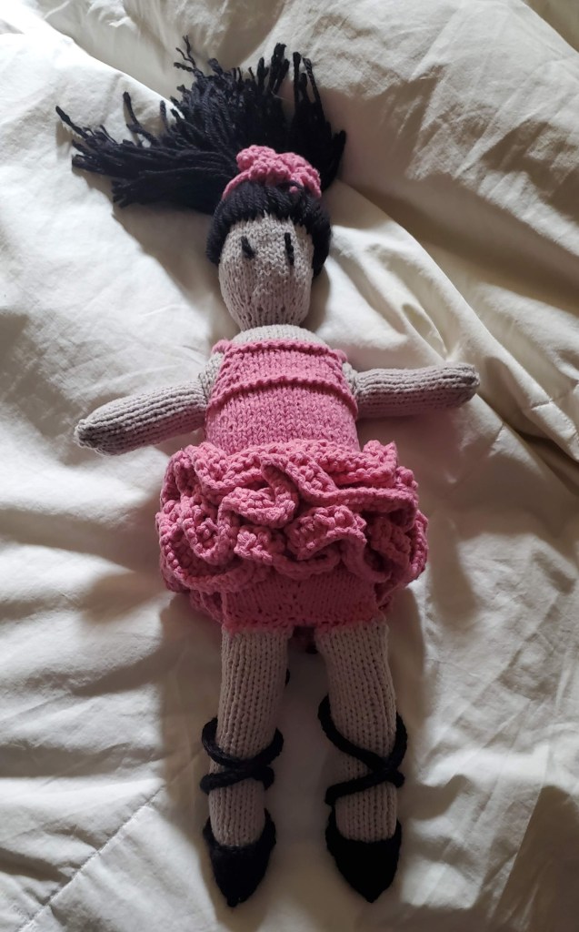 knitting project of a ballerina doll wearing a pink tutu and camisole and black slippers