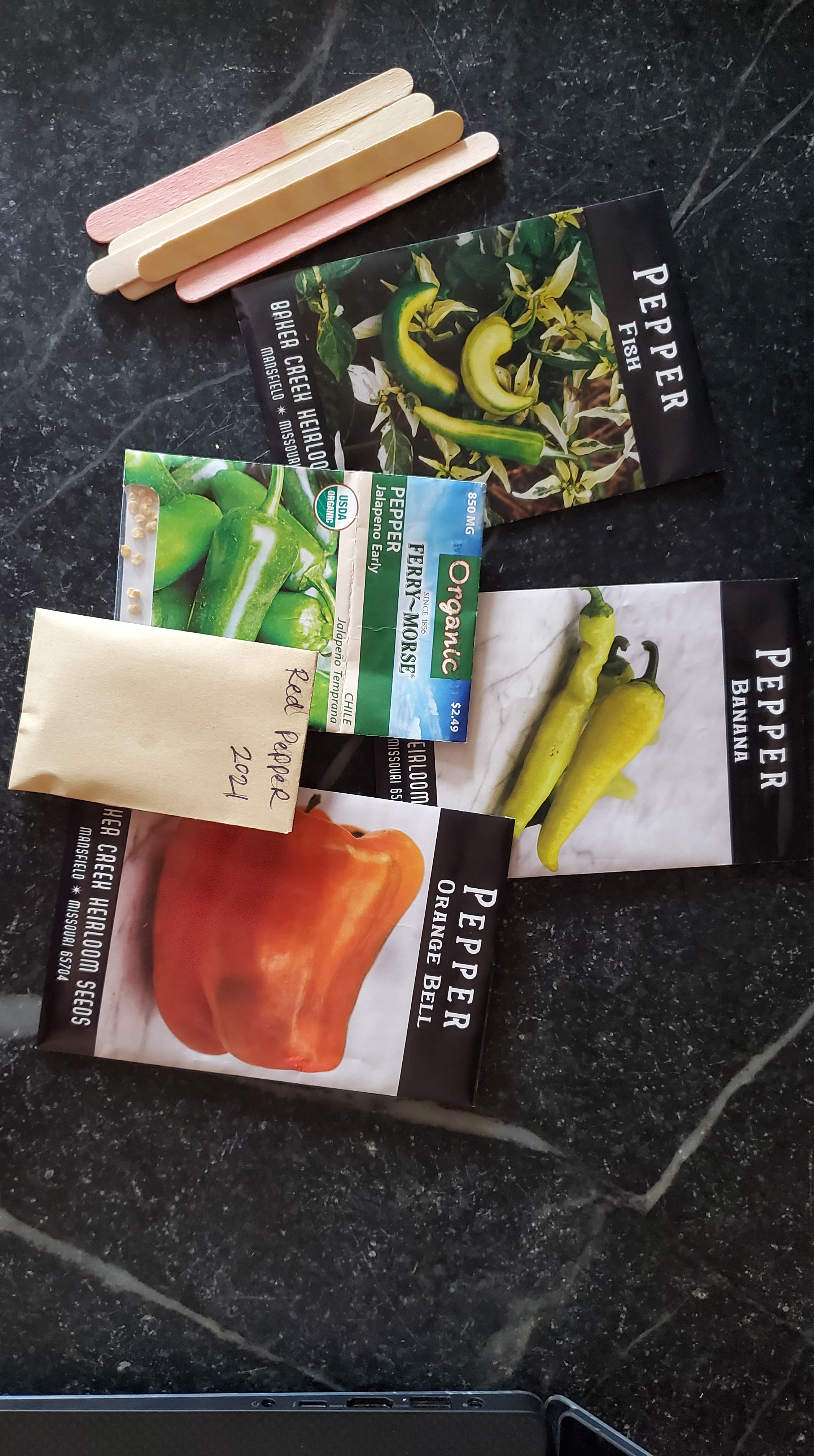 Five pepper seed packets and five popsicle sticks for seed start